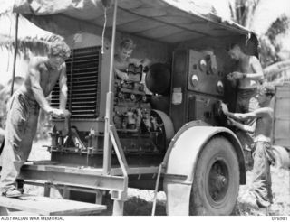 JACQUINOT BAY, NEW BRITAIN. 1944-11-17. PERSONNEL OF THE 472ND HEAVY ANTI-AIRCRAFT TROOP CHECKING THE DIESEL POWER UNIT WHICH OPERATES THE UNIT PORTABLE RADAR SET SITUATED IN THE WUNUNG PLANTATION. ..