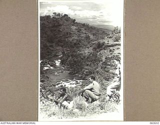 LALOKI RIVER, NEW GUINEA. 1944-01-02. QX53335 DRIVER D. KURTZ, HEADQUARTERS, NEW GUINEA FORCE (1) AND SERGEANT H. J. SMITH (2) RELAXING AFTER A CLIMB UP INTO THE HILLS. THE VIEW LOOKS TOWARDS ..