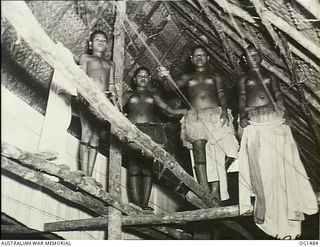 KIRIWINA, TROBRIAND ISLANDS, PAPUA. C. 1944-03. LOCAL PAPUAN NATIVE WOMEN, JILL TOOTS, MATILDA AND JOSEPHINE, HANG WASHING IN A NATIVE BUILT HUT USED AS A DRYING ROOM AT NO. 46 OPERATIONAL BASE ..