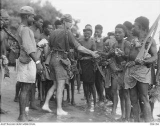 TINIAN, BOUGAINVILLE. 1945-07-18. FLIGHT LIEUTENANT N.C. SANDFORD, ALLIED INTELLIGENCE BUREAU, SHAKING HANDS WITH HIS NATIVES BEFORE LEAVING FOR TOROKINA ON THE MOTOR LAUNCH ML1327, ON THE OCCASION ..