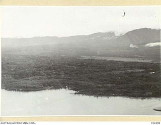 MILNE BAY, PAPUA. 1942-09. LOOKING DOWN OVER GILI GILI, SHOWING THE MAIN AIRSTRIP IN THE MIDDLE RIGHT AND MOUNTAINS IN DISTANCE