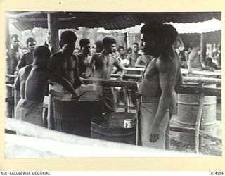 MALAMAL, NEW GUINEA. 1944-07-13. NATIVE COOKS SERVING OUT RICE DURING THE EVENING MEAL PARADE AT THE AUSTRALIAN NEW GUINEA ADMINISTRATIVE UNIT NATIVE LABOUR COMPOUND