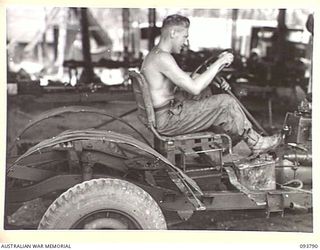 PALMALMAL PLANTATION, JACQUINOT BAY, NEW BRITAIN, 1945-06-06. SERGEANT K. BOUCHER, 1 INFANTRY TROOPS WORKSHOP, ON AN IMPROVISED SEAT PLACED ON THE CHASSIS OF A JEEP FOR THE DRIVER TO TEST IT BEFORE ..