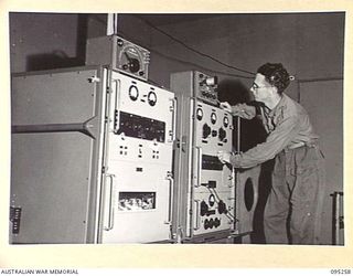 JACQUINOT BAY, NEW BRITAIN, 1945-08-12. CRAFTSMAN W.G. MORRISON, FORMERLY A STATION ENGINEER AT 7HO HOBART, OPERATES THE TEMPORARY TRANSMITTER AT THE NEW AUSTRALIAN ARMY AMENITIES SERVICE RADIO ..