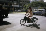 French Polynesia, woman riding motorized bicycle in Papeete