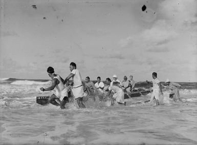 [Group of men pulling a canoe across water]