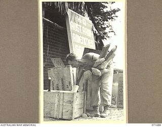 LAE, NEW GUINEA. 1944-03-25. PRIVATE T. L. ROBSON OF HEADQUARTERS LAE BASE SUB-AREA UNPACKING SPORTING MATERIAL AT HEADQUARTERS ARMY AMENITIES SERVICE