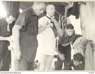 MILILAT, NEW GUINEA. 1944-08-23. MEMBERS OF THE "TASMANIACS", THE TASMANIAN LINES OF COMMUNICATION CONCERT PARTY ADOPT MAKESHIFT METHODS TO MAKE UP FOR THE LACK OF DRESSING ROOM ACCOMMODATION. ..