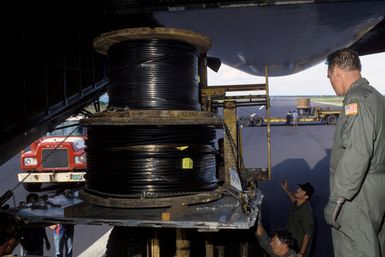 Members of the 22nd Military Airlift Squadron and local Samoans unload electrical generator cable from the rear of a C-5 Galaxy aircraft at the Pago Pago International Airport