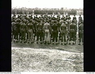 CAPE WOM AIR-STRIP, WEWAK SECTOR, NEW GUINEA, 1945-09-13. 6TH DIVISION, AIF, 'STANDS AT EASE' AS LIEUTENANT-GENERAL HATAZO ADACHI, COMMANDER OF THE JAPANESE 18TH ARMY, IS MARCHED THE LENGTH OF THE ..