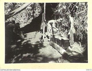 BOUGAINVILLE ISLAND. 1945-02-14. Q104699 SERGEANT G.W. HAMMOND (1) N150711 PRIVATE T.A. HORNER (2) AND Q114498 PTE J.F. FARRY (3) COOKS OF THE 61ST INFANTRY BATTALION PREPARING A MEAL IN THEIR ..