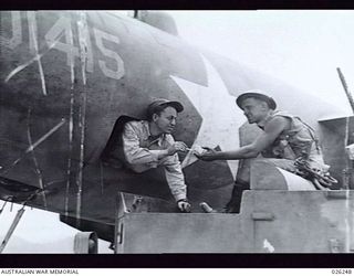 NEW GUINEA, 1942-08-11. "HAVE ONE OF THESE YANK". A MEMBER OF THE 39TH INFANTRY BATTALION, AUSTRALIAN MILITARY FORCES FROM A BREN GUN CARRIER FRATERNIZES WITH THE BOMB AIMER OF A GIANT AMERICAN ..
