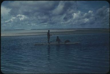 Islands of the atoll's ring, two people in outrigger canoe in foreground : Mortlock Islands, Papua New Guinea, 1960 / Terence and Margaret Spencer