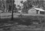 Village scene: church building (r), people carry bundles slung from poles