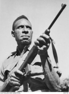 Portrait of Simogun Pita, a New Guinea native coastwatcher, armed with a M1 Carbine. In the 1960's he served as Assistant Parliamentary Under-Secretary for Police in the Territory of Papua and New ..