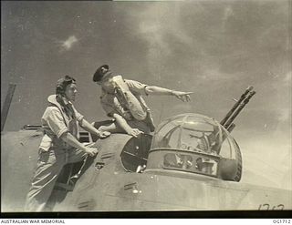 TADJI NEAR AITAPE, NORTH EAST NEW GUINEA. C. 1944-09. A MEMBER OF THE CREW OF A BEAUFORT BOMBER AIRCRAFT (RIGHT) EXPLAINING TO A US AIR FORCE AIRACOBRA PILOT ABOUT THE REAR GUN TURRET OF HIS BOMBER