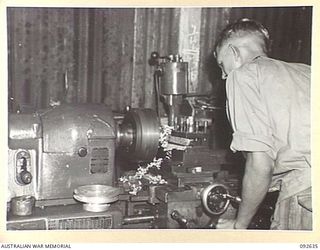 PURUATA ISLAND, SOUTH BOUGAINVILLE. 1945-05-29. SAPPER S. AMBROSE, 42 LANDING CRAFT COMPANY, WORKING ON A LATHE IN THE UNIT WORKSHOP. THIS COMPANY HAS PLAYED AN IMPORTANT PART IN SUPPLYING FORWARD ..