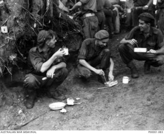 THE SOLOMON ISLANDS, 1945-03-27. AUSTRALIAN SOLDIERS PARTAKING OF A MEAL ON THE NUMA NUMA TRAIL ON BOUGAINVILLE ISLAND. (RNZAF OFFICIAL PHOTOGRAPH.)