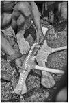 Ritual exchange: man measures strand of cowrie shells against blade of stone axe