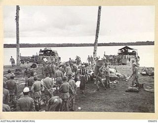 KAIRIRU ISLAND, NEW GUINEA. 1945-09-17. THE BEACH HEAD SCENE AS JAPANESE NAVAL PERSONNEL BEING TRANSFERRED BY BARGE TO MUSCHU ISLAND HURRY TO AND FRO LOADING THEIR GEAR. FOLLOWING THE SURRENDER OF ..