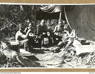 KILIGIA BEACH, NEW GUINEA. 1943-12-28. MEMBERS OF NO. 11 BATTERY 2/3RD TANK ATTACK REGIMENT ENJOY A CUP OF MORNING TEA. THEY ARE: NX38430 GUNNER J. R. BURKHARDT (1); NX60394 GUNNER L. GALVIN (2); ..