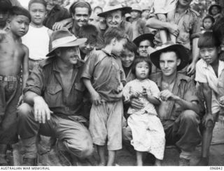 RATONGOR, NEW BRITAIN. 1945-09-18. AUSTRALIAN TROOPS PICTURED WITH CHINESE CHILDREN AT THE CHINESE CIVILIAN INTERNMENT CAMP AFTER THE SURRENDER OF THE JAPANESE