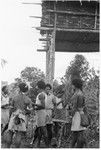 Men standing under raised house at feast