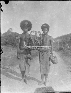 Two men holding a model of a lakatoi, a sailing canoe, Papua, ca. 1923 / Sarah Chinnery