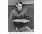 Lauren R. Donaldson holding a rainbow trout with dorsal and adipose fin removed, Bikini Atoll, January 12, 1948