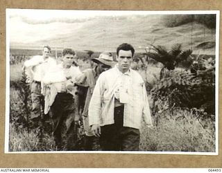 MELBOURNE, VICTORIA, AUSTRALIA. 1944-03-03. COPY OF A SCENE FROM A CINE STRIP OF AUSTRALIAN WALKING WOUNDED MOVING ALONG A TRACK IN THE HIGHLANDS OF NEW GUINEA