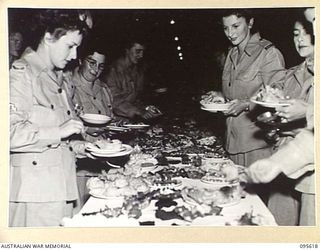 LAE AREA, NEW GUINEA. 1945-08-31. AUSTRALIAN ARMY MEDICAL WOMEN'S SERVICE MEMBERS OF 2/7 GENERAL HOSPITAL HELPING THEMSELVES TO BUFFET TEA HELD IN THE AUSTRALIAN ARMY MEDICAL WOMEN'S SERVICE MESS