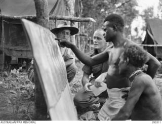 BOUGAINVILLE. 1945-04-03. NAGOVISSI NATIVES INDICATING JAPANESE POSITIONS AND TRACKS ON MOSAIC PHOTOGRAPHS TO CAPTAIN F.D. PERCIVAL, GENERAL STAFF OFFICER 3 (AIR), 3 DIVISION (1), AND LIEUTENANT ..