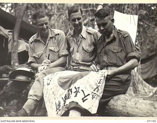 FORTIFICATION POINT, NEW GUINEA, 1944-03-15. MEMBERS OF THE 32ND FIELD SECURITY SECTION, INTELLIGENCE CORPS ADDING THEIR AUTOGRAPHS TO THOSE OF JAPANESE SOLDIERS ON A CAPTURED JAPANESE FLAG. ..
