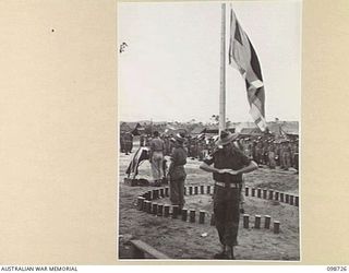 DALLMAN HARBOUR, NEW GUINEA. 1945-11-11. THE BUGLER SOUNDING THE LAST POST AT THE SALUTING BASE AS THE FLAG IS LOWERED TO HALF MAST, DURING A MEMORIAL SERVICE CONDUCTED IN THE UNIT LINES BY ..