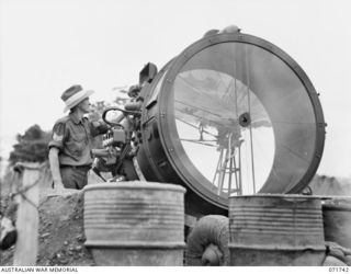 LAE, NEW GUINEA, 1944-03-26. NX114435 SERGEANT G. L. MARTIN, 73RD MOBILE SEARCHLIGHT BATTERY AT THE 2/3RD ANTI-AIRCRAFT REGIMENT (COMPOSITE) DIRECTS A SPERRY PROJECTOR 150CM SEARCHLIGHT