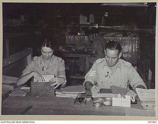 LAE, NEW GUINEA. 1945-05-15. DRIVER B. FULLER (1), AT SUPPLY AND TRANSPORT, HEADQUARTERS FIRST ARMY, RECEIVING INSTRUCTION IN REGISTRY AND FILLING FROM SERGEANT O.W. BRAILEY (2). A FEW DAYS AFTER ..
