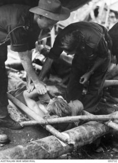 WEWAK AREA, NEW GUINEA, 1945-06-29. CAPTAIN A.J. MOONEY, REGIMENTAL MEDICAL OFFICER, 2/8 INFANTRY BATTALION (1) TREATING CORPORAL L.H. LENG (3) IN THE REGIMENTAL AID POST AT BATTALION HEADQUARTERS. ..