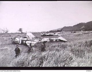 DAGUA, NEW GUINEA. 1945-03-25. MEMBERS OF THE 2/2ND INFANTRY BATTALION MOVING FROM THE BIVOUAC AREA AT THE AIRSTRIP, PASS THE WRECKAGE OF JAPANESE AIRCRAFT