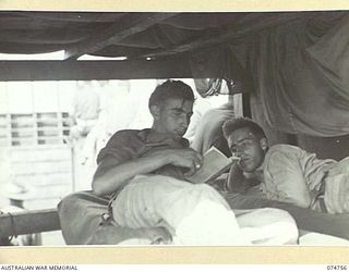 AT SEA. 1944. MEMBERS OF THE CREW OF THE COURIER BARGE OF THE 593RD UNITED STATES BARGE COMPANY RELAXING IN THEIR BUNKS DURING THE RETURN TRIP TO MADANG