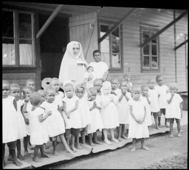 Nun with an assistant and a group of children on a verandah, Vunapope Sacred Heart Mission, Kokopo, New Guinea, 1937, 2 / Sarah Chinnery