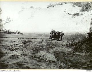 LANGEMAK BAY, NEW GUINEA. 1944-03-20. THIS CUT ON MARSH ROAD MADE BY C COMPANY, 870TH UNITED STATES AVIATION ENGINEER BATTALION MEASURING 80 FEET DEEP, 60 FEET WIDE AND 200 YARDS LONG ALLOWED THE ..