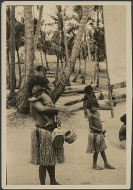 Woman wearing a grass skirt holding an infant and two baskets, Port Moresby, Papua, ca. 1923, 2 / Sarah Chinnery
