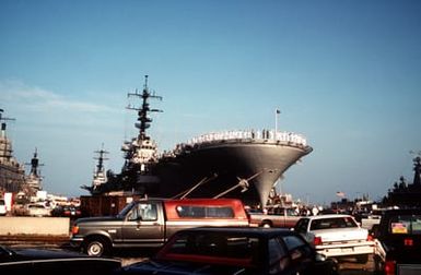 Crew members man the rails as the amphibious assault ship USS GUAM (LPH-9) prepares to depart for the Middle East in support of Operation Desert Shield