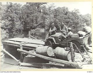 1943-05-19. NEW GUINEA. ORO BAY. A JEEP WAITS ON LANDING FOR TRANSPORT BY PONTOON FERRY ACROSS THE RIVER AT ORO BAY. NATIVES HAUL THE PONTOON BACKWARDS AND FORWARDS. (NEGATIVE BY N. BROWN)