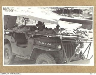 12 MILE, PORT MORESBY AREA, NEW GUINEA. 1943-12-03. DEMONSTRATION OF A NEW JEEP AMBULANCE DESIGNED AND BUILT BY THE TROOPS OF THE 2ND AUSTRALIAN MOTOR AMBULANCE CONVOY. SHOWN ARE: NX139809 DRIVER ..