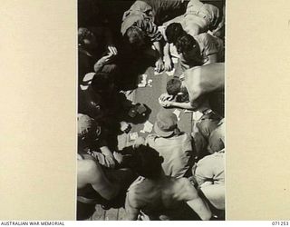 AT SEA, 1944-03. AUSTRALIAN AND AMERICAN SOLDIERS PLAYING STUD POKER ON THE AFTER DECK OF THE TROOPSHIP HT TAROONA EN ROUTE TO MILNE BAY FROM TOWNSVILLE, QUEENSLAND