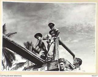 JACQUINOT BAY, NEW BRITAIN, 1945-05-20. MR. K. WATTS, YOUNG MEN'S CHRISTIAN ASSOCIATION REPRESENTATIVE (1), WITH SERGEANT R.W. THOMAS (2), AND MAJOR C.R. AITKEN (3), BROADCASTING RESULTS AND ..