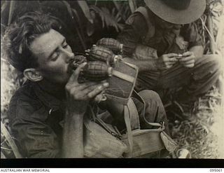 Panamberi River, New Guinea. 1945-08-05. NX86671 Private S. Hill, 2/7th Australian Infantry Battalion, AIF, takes a drink from his water bottle to which is attached part of his supply of grenades. ..