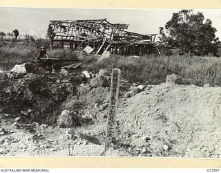 MADANG, NEW GUINEA. 1944-04-25. AN INSCRIBED JAPANESE MEMORIAL SITUATED ALONGSIDE A BOMB CRATER. AN AUSTRALIAN LIEUTENANT STANDS ALONGSIDE A BOMB DAMAGED JAPANESE 75MM ANTI-AIRCRAFT GUN AT THE ..