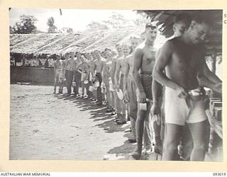 MOROKAIMORO, BOUGAINVILLE, 1945-06-06. PERSONNEL QUEUEING UP FOR MESS AT HQ, 2/8 COMMANDO SQUADRON. LONG RANGE PATROLS OPERATE FROM THIS UNIT CARRYING OUT HARRASSING RAIDS AND AMBUSHES AGAINST THE ..